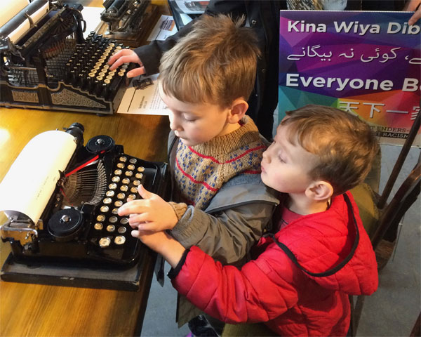 Two children typing on a 1920s Underwood portable.